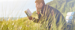 Photograph of a man reading in tall grass
